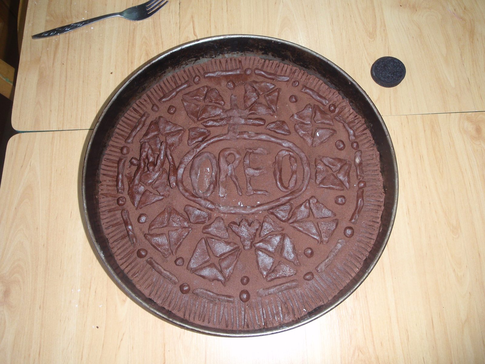 Finished embossed OREO top in its tin, a real Oreo alongside showing the scale